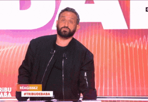 a man with a beard stands at a podium with a sign that says reagissez #tribunebaba