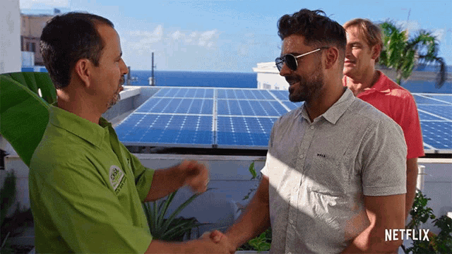a man in a green shirt shakes hands with a man in a gray shirt
