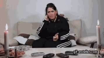 a woman is sitting on a couch talking on a cell phone next to candles .