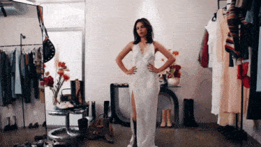 a woman in a white dress stands with her hands on her hips in front of a mirror