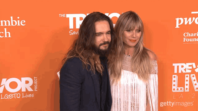 a man and a woman are posing for a picture on a red carpet that says the tp project