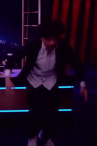 a man in a suit and a white shirt is dancing