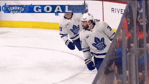 two toronto maple leafs hockey players on the ice celebrating a goal