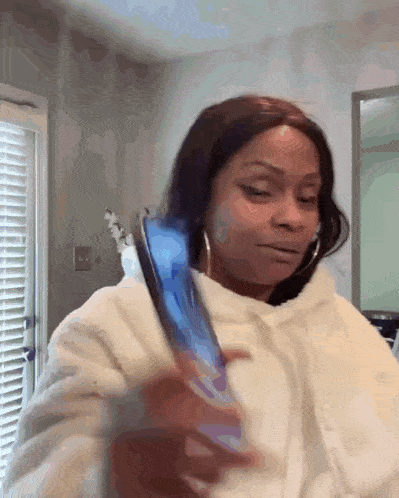 a woman in a white hoodie is holding a blue cell phone in her hand .