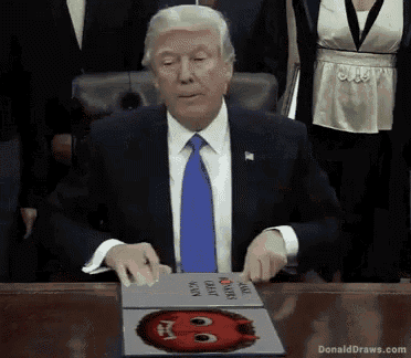 donald trump is sitting at a table with a book open to a page that says ' donald draws ' on it