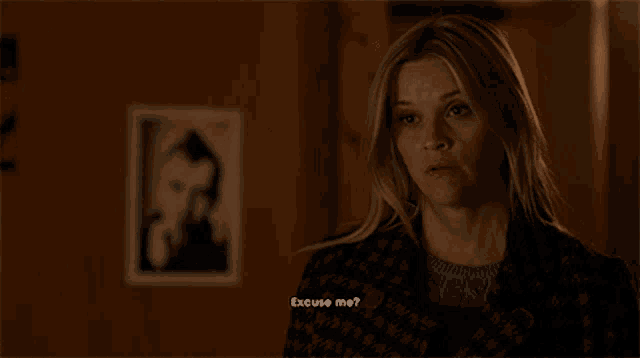 a woman says excuse me in front of a picture of a man