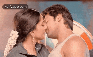 a man and a woman are kissing each other on the forehead .