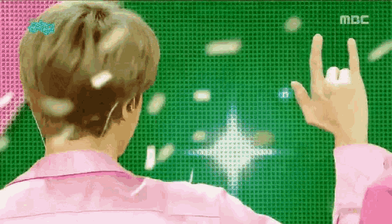 a man in a pink shirt is standing in front of a mbc screen