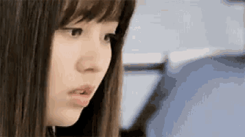a close up of a woman 's face with her mouth open and a man in the background .