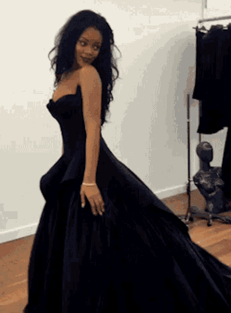 a woman in a black dress is standing in a room .