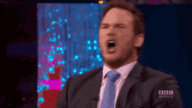 a man in a suit and tie is screaming in front of a bbc america sign