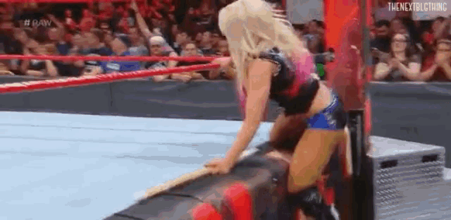 a woman is kneeling down in a wrestling ring while holding a wooden stick .