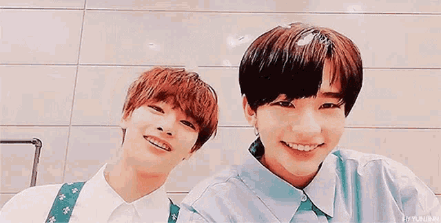 a couple of young men standing next to each other and smiling .