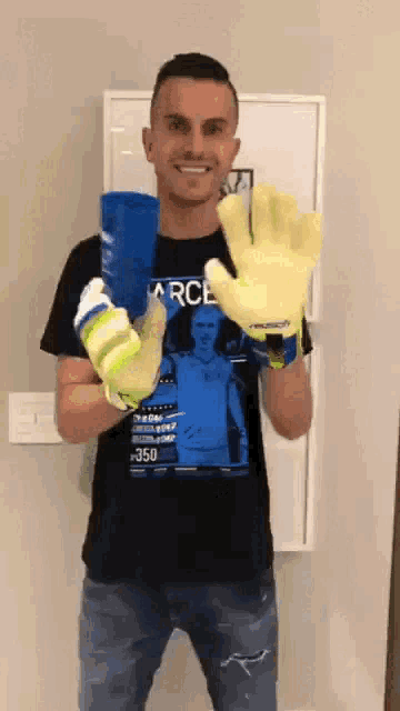 a man wearing a black shirt with the word arce on it is holding a pair of gloves