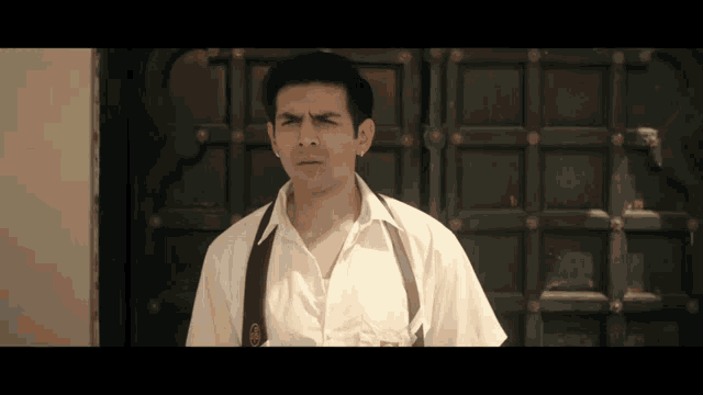 a man in a white shirt and suspenders has a badge on his pocket that says ' a ' on it