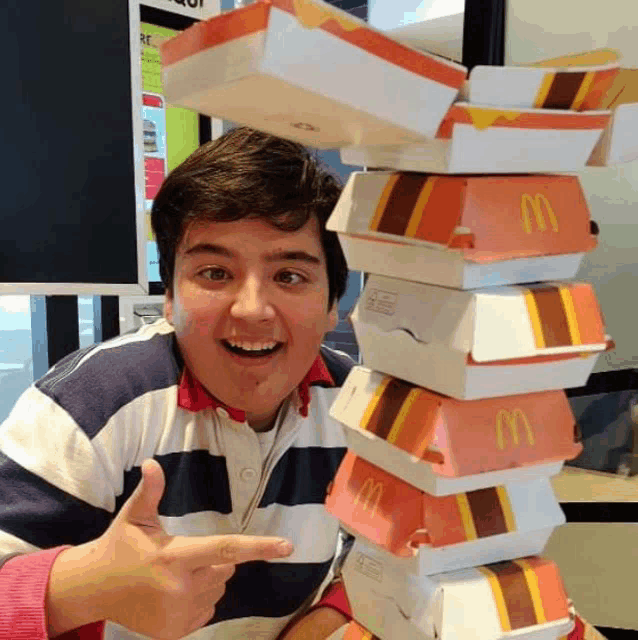 a man is holding a stack of mcdonald 's boxes and giving a thumbs up
