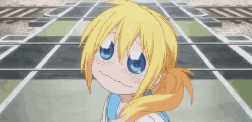 a girl with blonde hair and blue eyes is making a funny face while standing on a street .