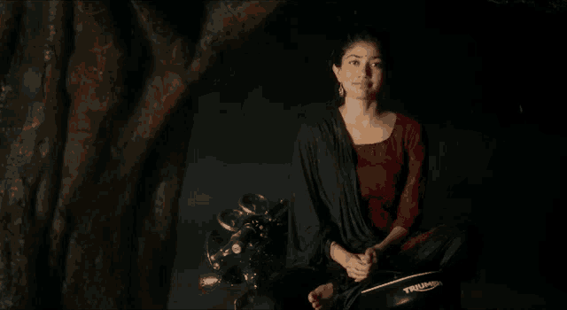 a woman is sitting on a triumph motorcycle and giving the middle finger