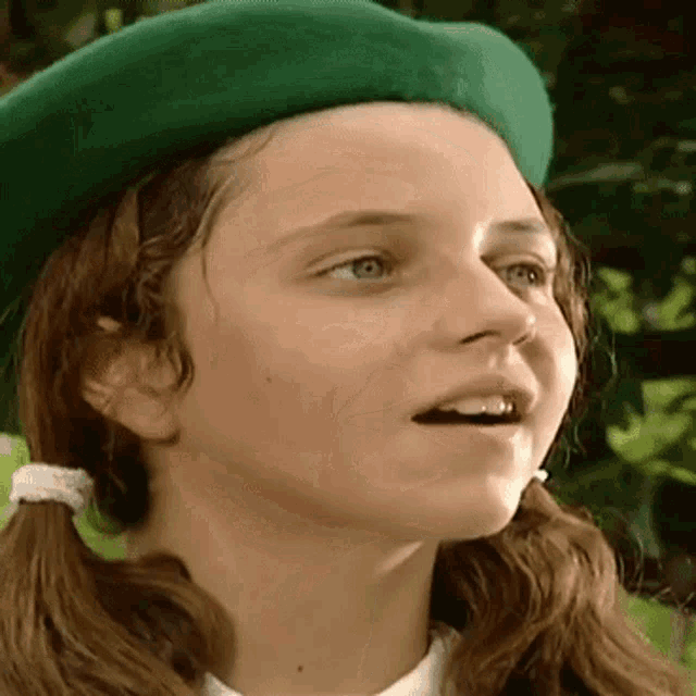 a young girl wearing a green beret looks at the camera