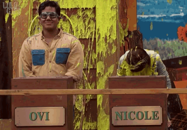 ovi and nicole are standing next to each other in front of boxes covered in slime