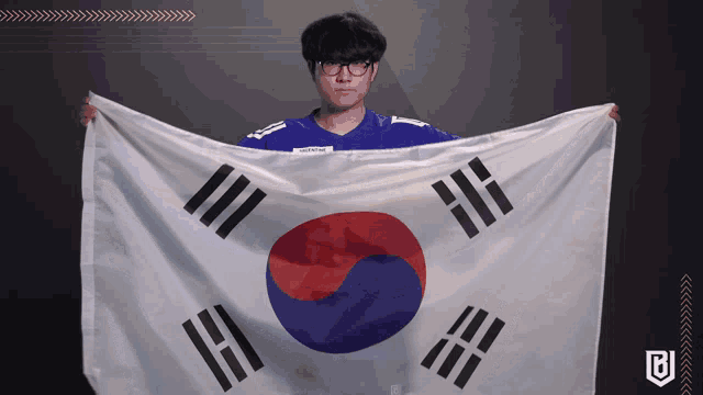 a man in a blue shirt is holding a korean flag in his hands