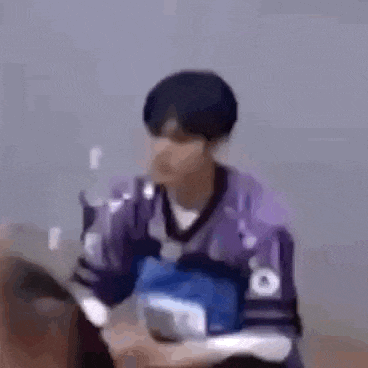 a man in a purple jersey is sitting in a chair and talking to someone .