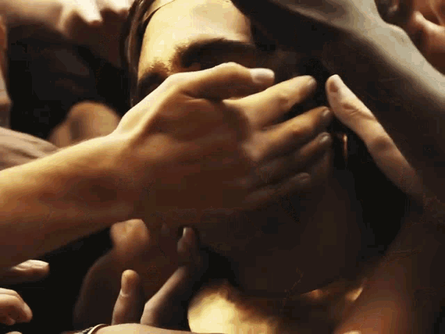 a group of people are touching a man 's face