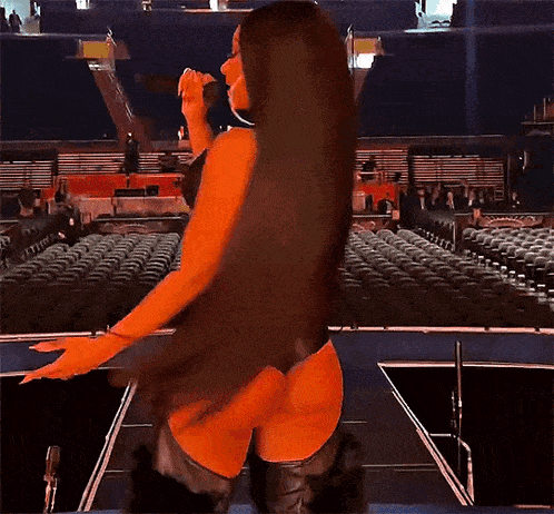 a woman in a bikini is singing into a microphone on stage .