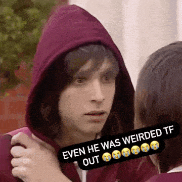 a young man in a red hoodie is looking at a girl .