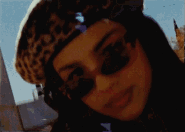 a close up of a woman wearing a leopard print hat and sunglasses