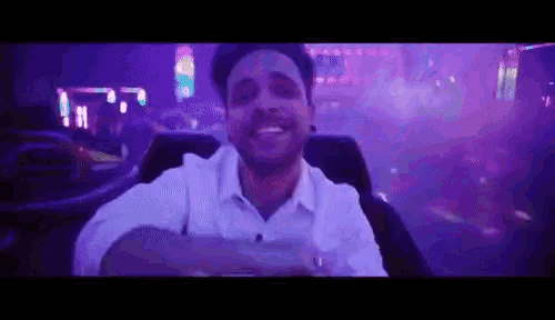 a man in a white shirt is smiling while sitting in a roller coaster .