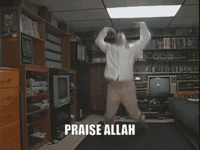 a man kneeling down in a living room with the words praise allah written on the screen