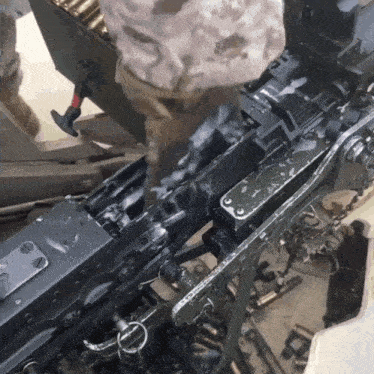 a soldier is working on a machine gun with a hammer