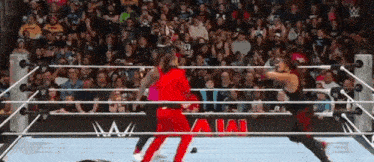 two wrestlers are fighting in a wrestling ring while a crowd watches .