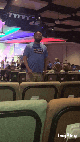 a man in a patagonia shirt stands in a crowded room