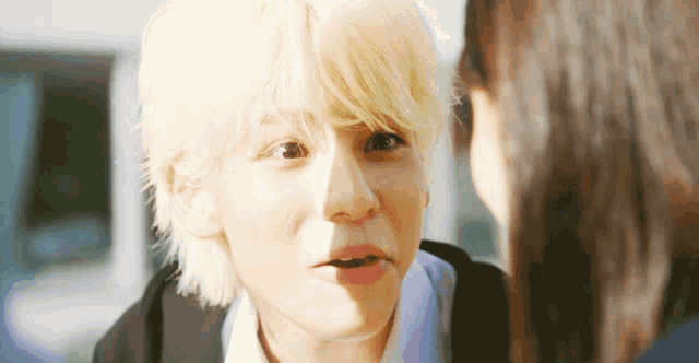 a boy with blonde hair is looking at a girl