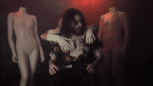 a man stands between two naked mannequins with no heads