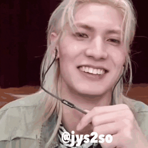 a man with long blonde hair is wearing headphones and smiling with the words @ jys2so below him