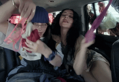 two women in a car one wearing a blue beanie and the other wearing glasses