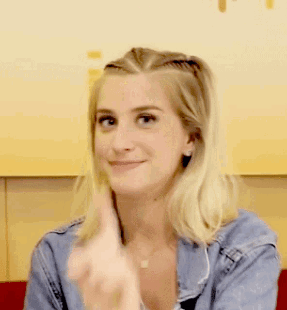a woman wearing a denim jacket is smiling and clapping