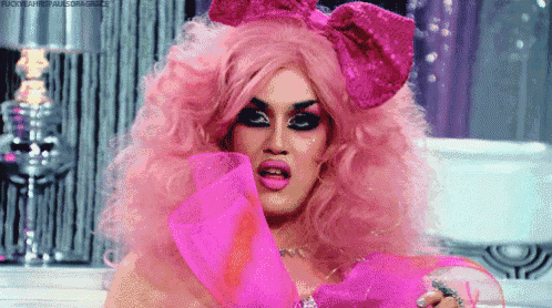 a drag queen with pink hair and a pink bow on her head