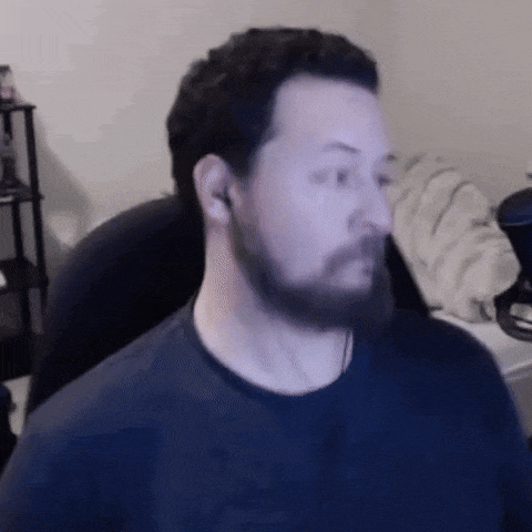 a man with a beard and ear buds is sitting in a chair in front of a computer screen .