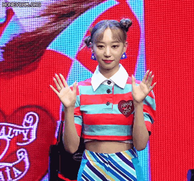 a woman in a striped shirt with a heart on it is waving at the camera