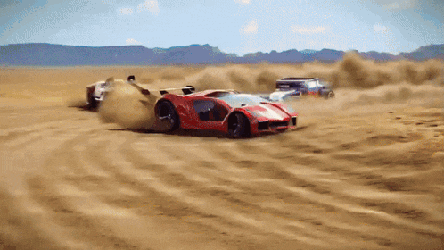 a red car is driving through a desert with other cars