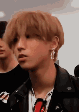 a close up of a person wearing a black leather jacket and earrings