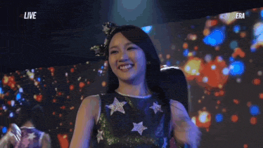 a woman holding a microphone in front of a screen that says live on it