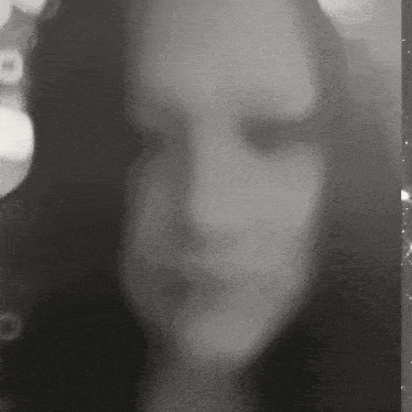 a black and white photo of a woman 's face with a blurry background of lights