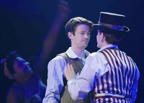 a man wearing a top hat stands next to another man