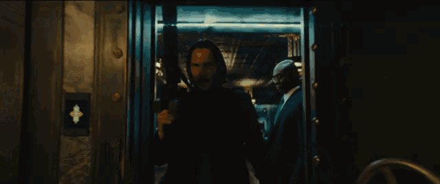 a man in a suit and tie is holding a gun in front of a vault door