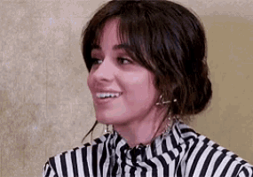 a close up of a woman wearing a striped shirt and earrings smiling .